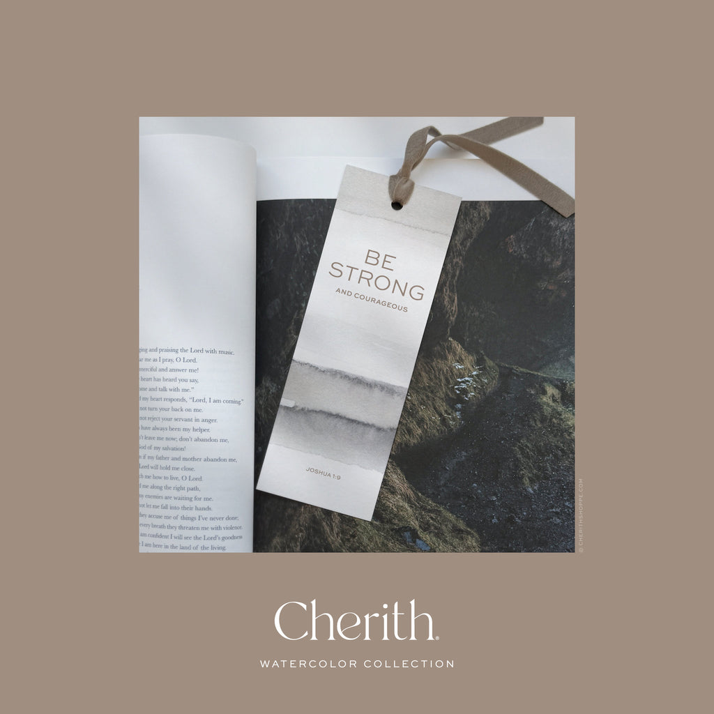 Be Strong Joshua 1:9 watercolor bookmark with a ribbon resting on a Bible, by Cherith.